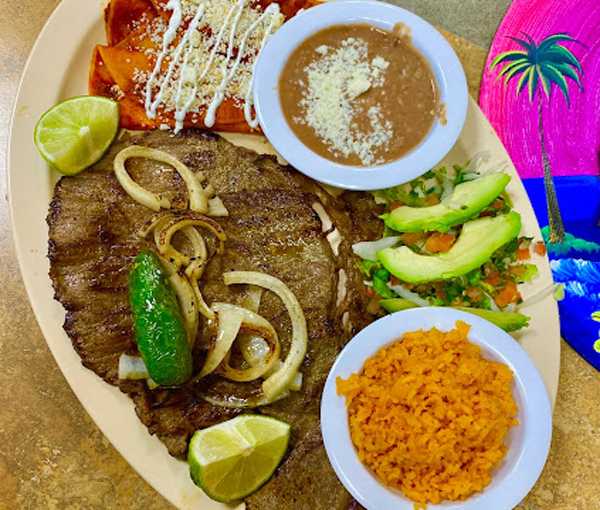 Mata Hambre platter with grilled steak, rice, beans, salad, guacamole, and tortillas